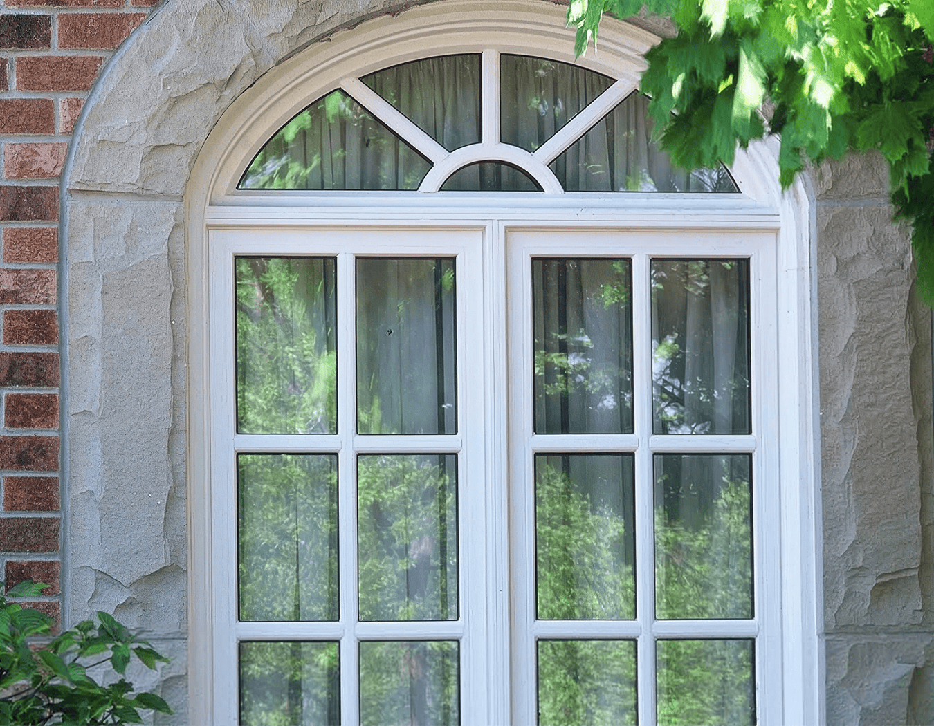 Arched window with white frame and curtains.