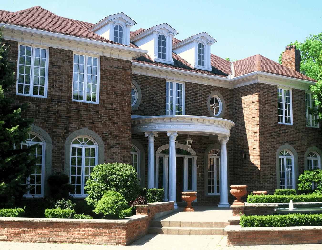 Large brick house with columns and garden.