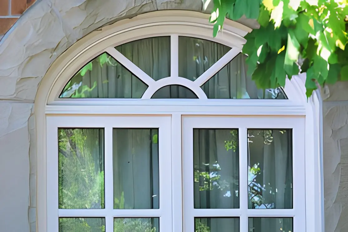 Arched window with leafy tree branches.
